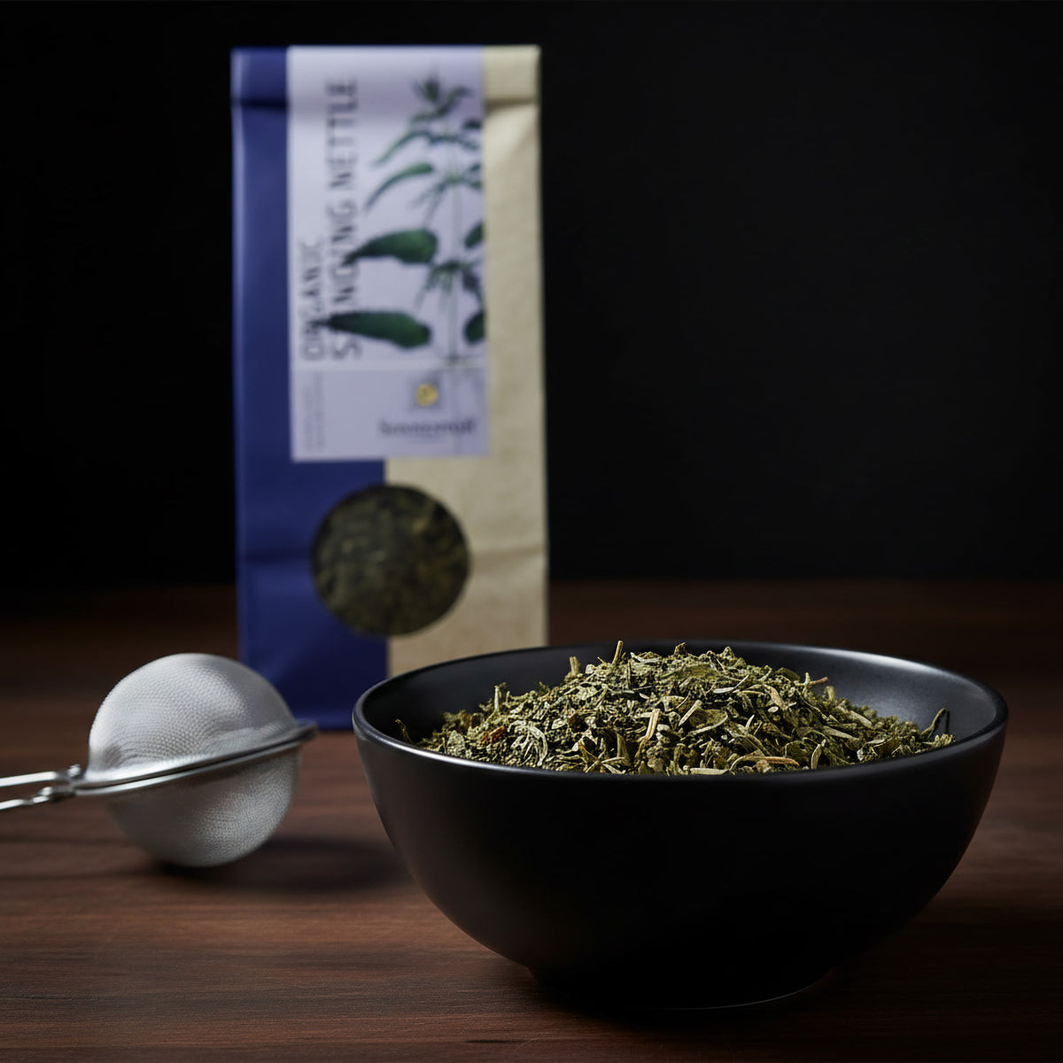 Generate a macro shot of the Sonnentor Bio Brennnessel Tee in a sophisticated, matte black bowl, with a focus on the leaf textures and subtle variations in green and brown hues. Use rim lighting to accentuate the natural contours and fine details of the te