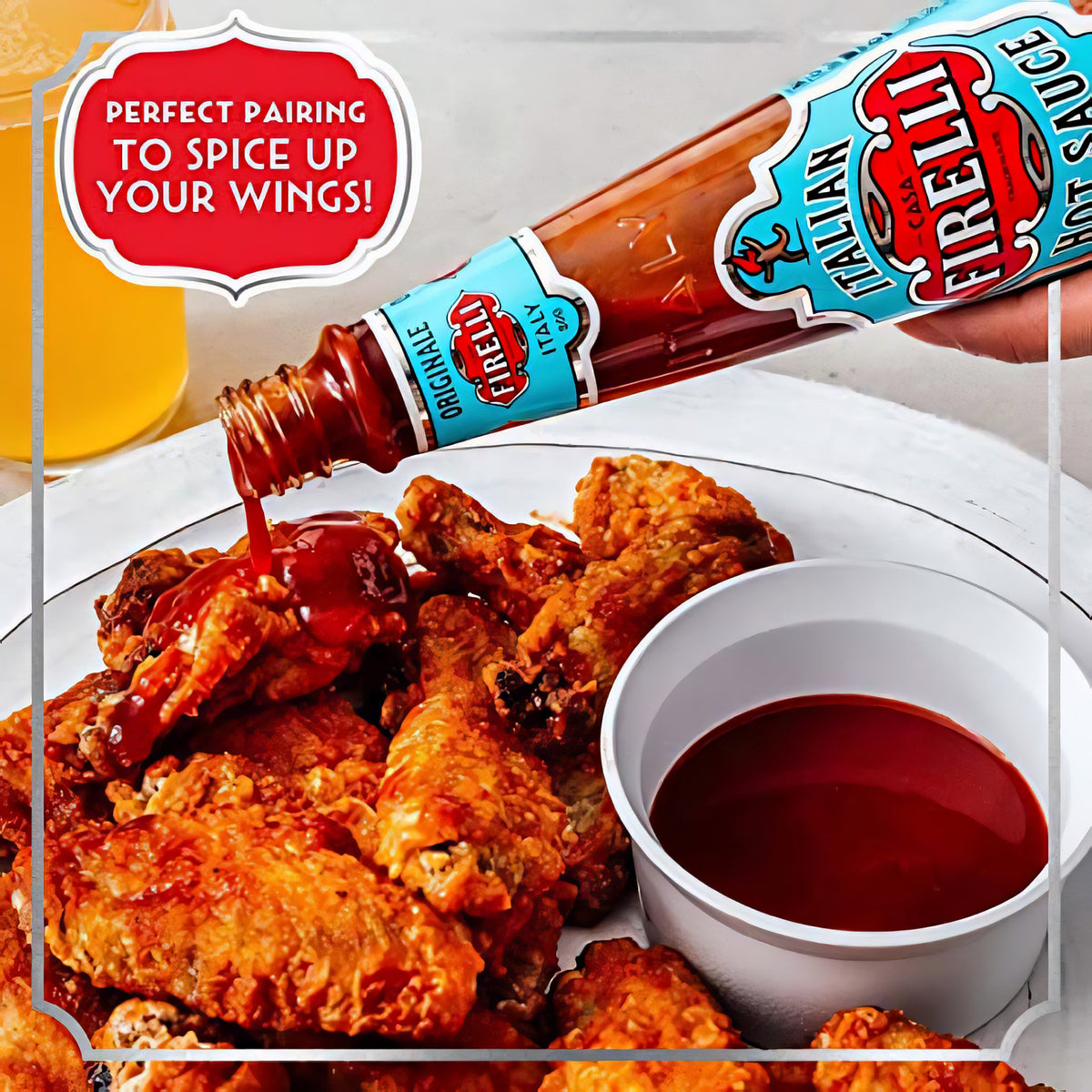 Firelli Hot Sauce aus Glasflasche wird als Sauce über knusprige Chicken Wings auf einem Teller gegossen.