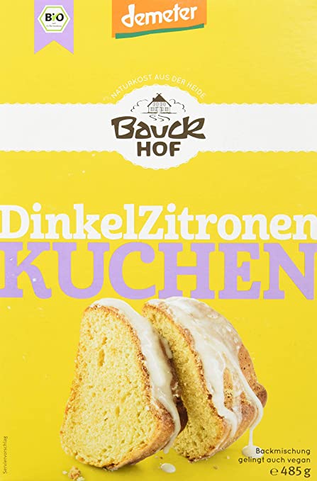 Bauck Demeter Dinkel Zitronenkuchen, gebacken, in Scheiben geschnitten, auf einem Teller, mit Zitronenscheiben und Puderzucker garniert