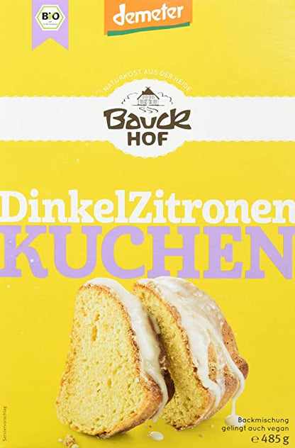 Bauck Demeter Dinkel Zitronenkuchen, gebacken, in Scheiben geschnitten, auf einem Teller, mit Zitronenscheiben und Puderzucker garniert