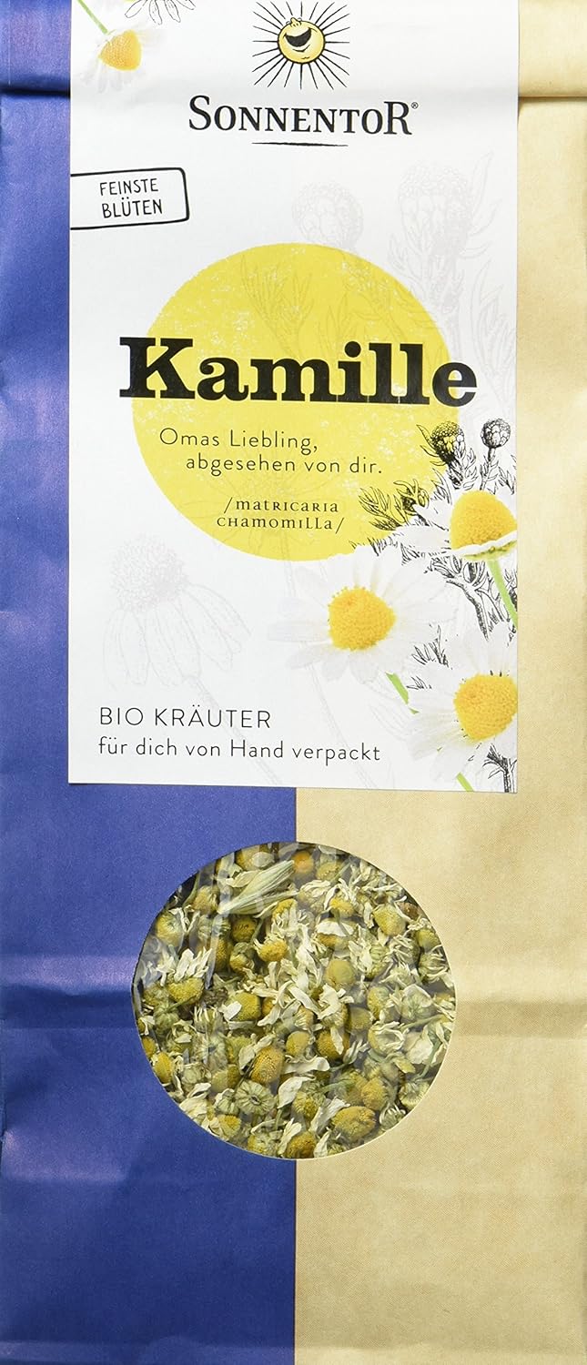 Bio Kamillentee von Sonnentor in einer offenen Teetasse mit Kamillenblüten und Teeblättern, Nahaufnahme
