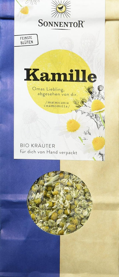 Bio Kamillentee von Sonnentor in einer offenen Teetasse mit Kamillenblüten und Teeblättern, Nahaufnahme