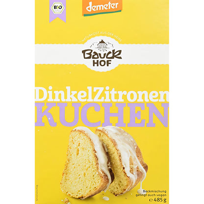 Bauck Demeter Dinkel Zitronenkuchen, gebacken, in Scheiben geschnitten, auf einem Teller, mit Zitronenscheiben und Puderzucker garniert