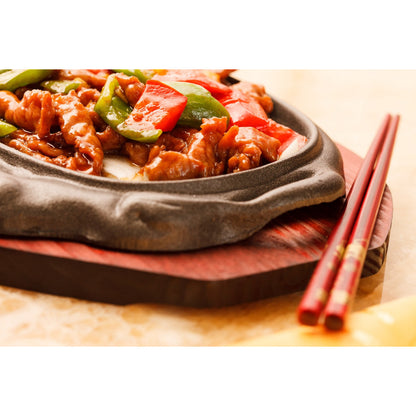 Asiatisches Gericht mit Gemüse und Fleisch in einer Pfanne, daneben rote Essstäbchen, geeignet zum Kochen mit Dulseflocken.