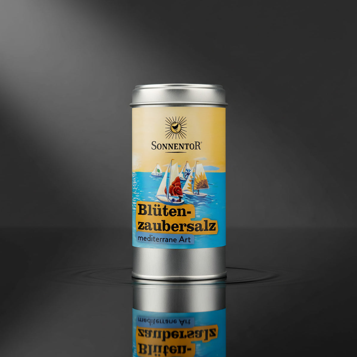 Illustrate a professional product shot in a sleek studio environment, with the 'Blütenzaubersalz' jar centered against a deep charcoal background for contrast. Use a single diffused daylight studio light source at a 45-degree angle to gently highlight the 