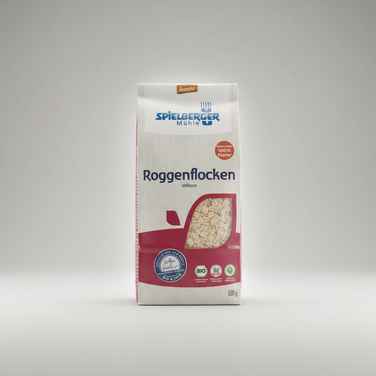 spielberger roggenflocken demeter 500g in Papierverpackung, frontal auf hellem Hintergrund stehend, das Sichtfenster zeigt die Flocken im Inneren