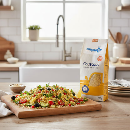 Plated couscous dish on a wooden platter in a modern kitchen, garnished with vegetables and herbs, showcasing versatility.