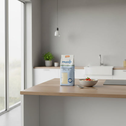Transparent bag of Spielberger Weichweizengrieß on wooden kitchen counter in a modern, bright setting, with a spoon and greenery nearby.