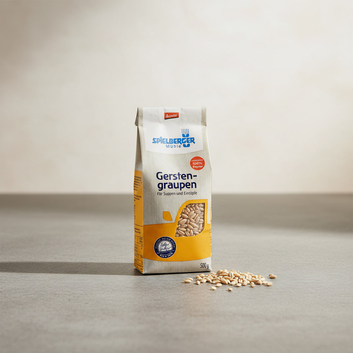 Small 500g organic barley packet on stone countertop with spilled grains, showcasing eco-friendly packaging and wholesome appeal.