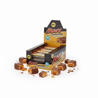 Mars Eiweißriegel in geöffneter Box, umgeben von aufgeschnittenen Riegelstücken mit sichtbarem Karamell und Keks.