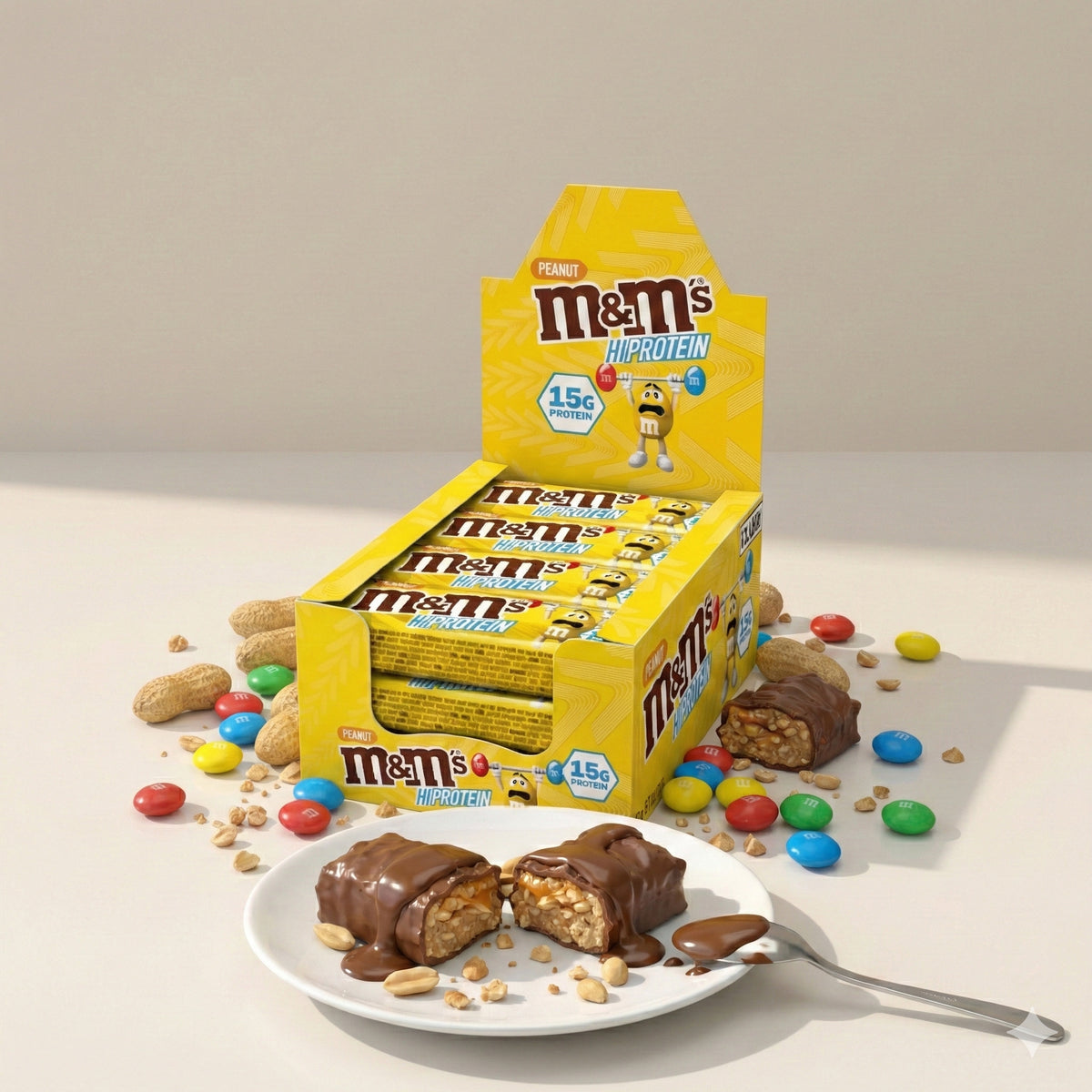 M&M's Protein Bar Eiweißriegel 12x51g in gelber Box, im Vordergrund ein halbierter Riegel auf einem Teller mit Erdnüssen, Schokosoße und Löffel als Protein Snack.