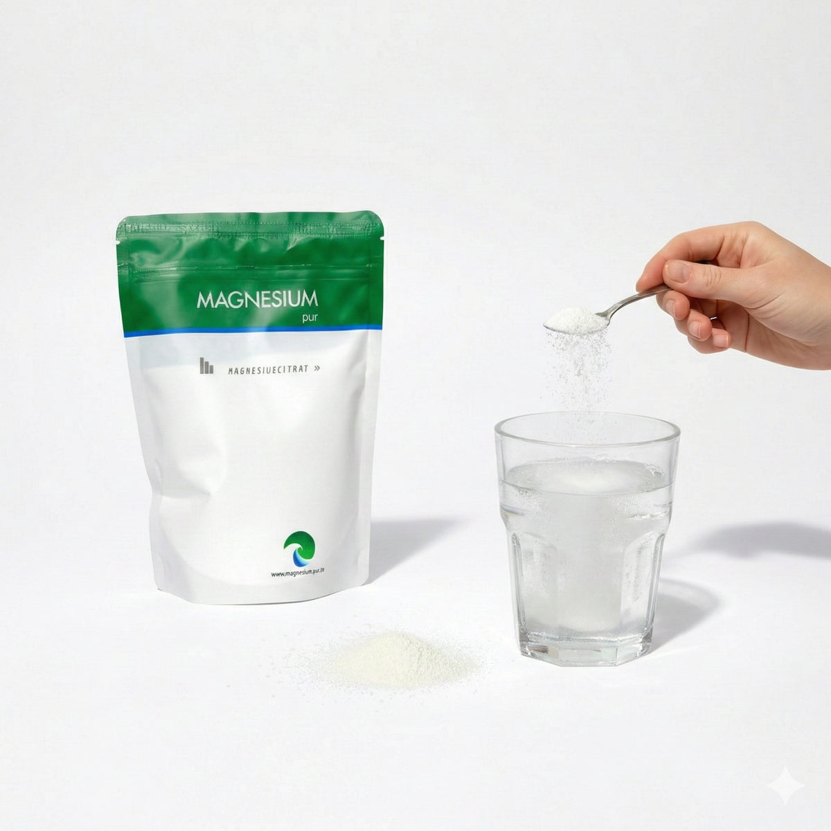 Ein Beutel Magnesiumcitrat Pulver 500g, daneben ein Glas Wasser, ein Löffel Pulver wird ins Glas eingerührt.