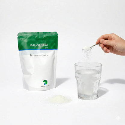 Ein Beutel Magnesiumcitrat Pulver 500g, daneben ein Glas Wasser, ein Löffel Pulver wird ins Glas eingerührt.