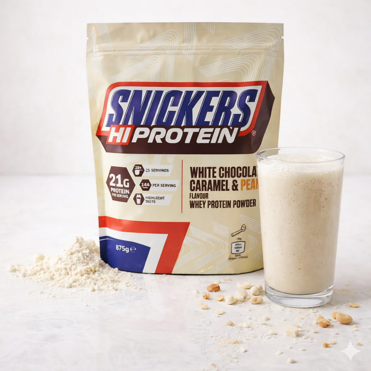 Snickers Whey Protein Beutel 875g neben Glas Proteinshake und verstreutem Pulver auf hellem Tisch