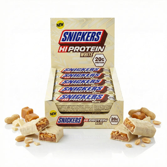 Snickers Hi-Protein White Bar 12x57g in geöffneter Verkaufspackung, vorne angeschnittene weiße schokoriegel mit sichtbaren Erdnüssen und Karamell, umgeben von Erdnüssen und Karamellstücken.