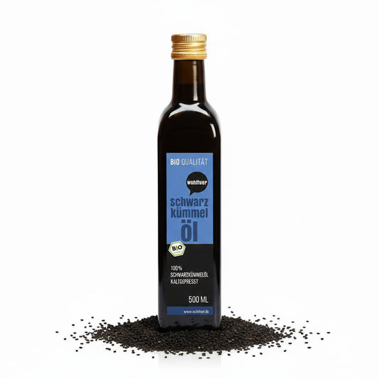 Flasche wohltuer Schwarzkümmelöl kaltgepresst, stehend auf einem Haufen Schwarzkümmel-Samen vor weißem Hintergrund.