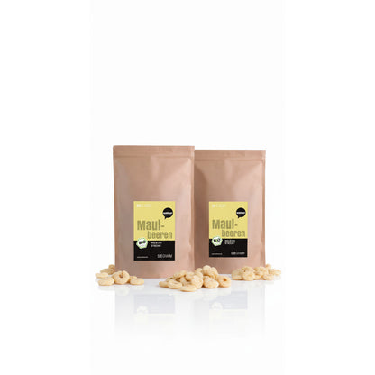 Zwei braune Beutel wohltuer Maulbeeren getrocknet 500g, umgeben von getrockneten Früchten auf weißem Untergrund.