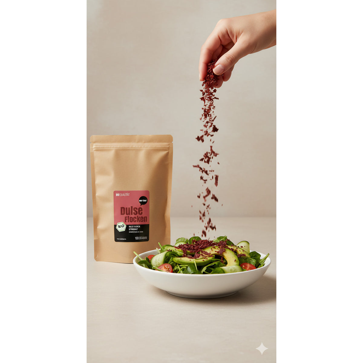Bio Dulseflocken von Wohltuer werden aus einer Hand über einen frischen Salat gestreut, Beutel im Hintergrund.