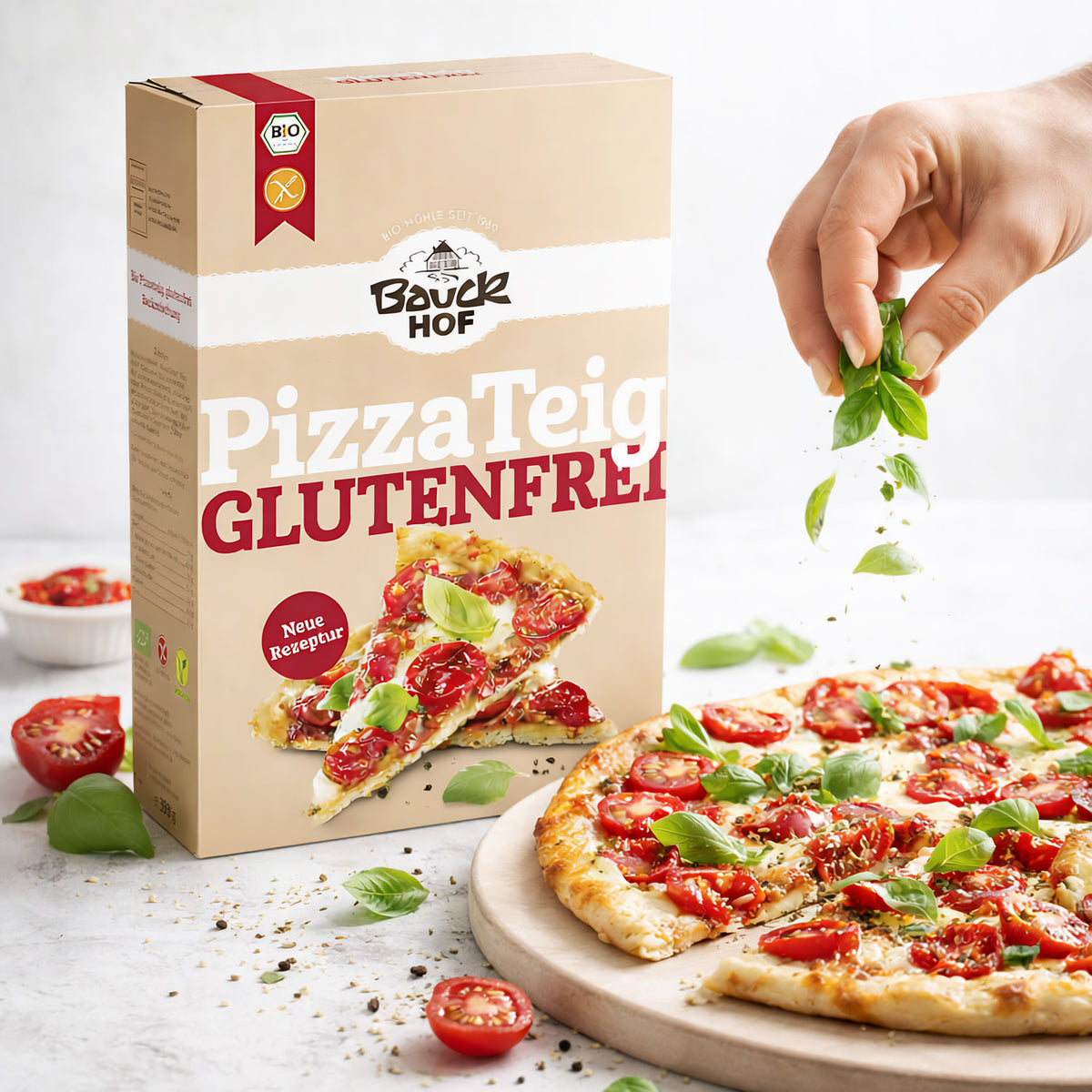 Bauck glutenfrei Pizzateig Backmischung neben einer Pizza, auf die frisches Basilikum gestreut wird.
