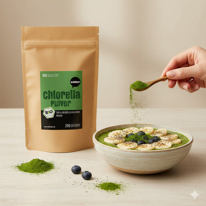 Beutel wohltuer Chlorella Pulver 250g neben einer Smoothie-Bowl, eine Hand streut grünes Algenpulver mit einem Löffel über die Bowl.