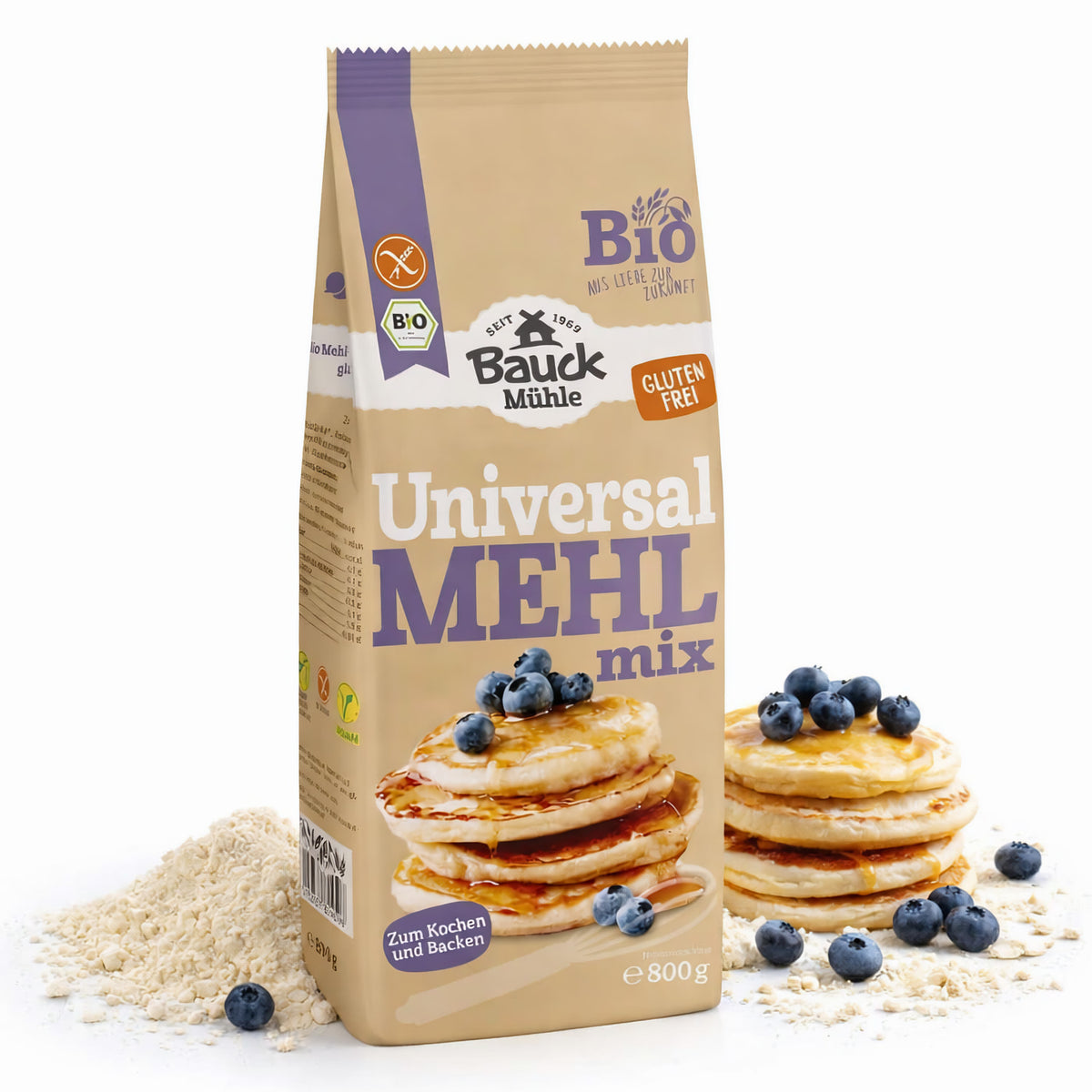 Packung Bauckhof Universal Mehl-Mix glutenfrei 800g neben einem Haufen Mehl, im Vordergrund Pancakes mit Blaubeeren auf Mehl liegend.
