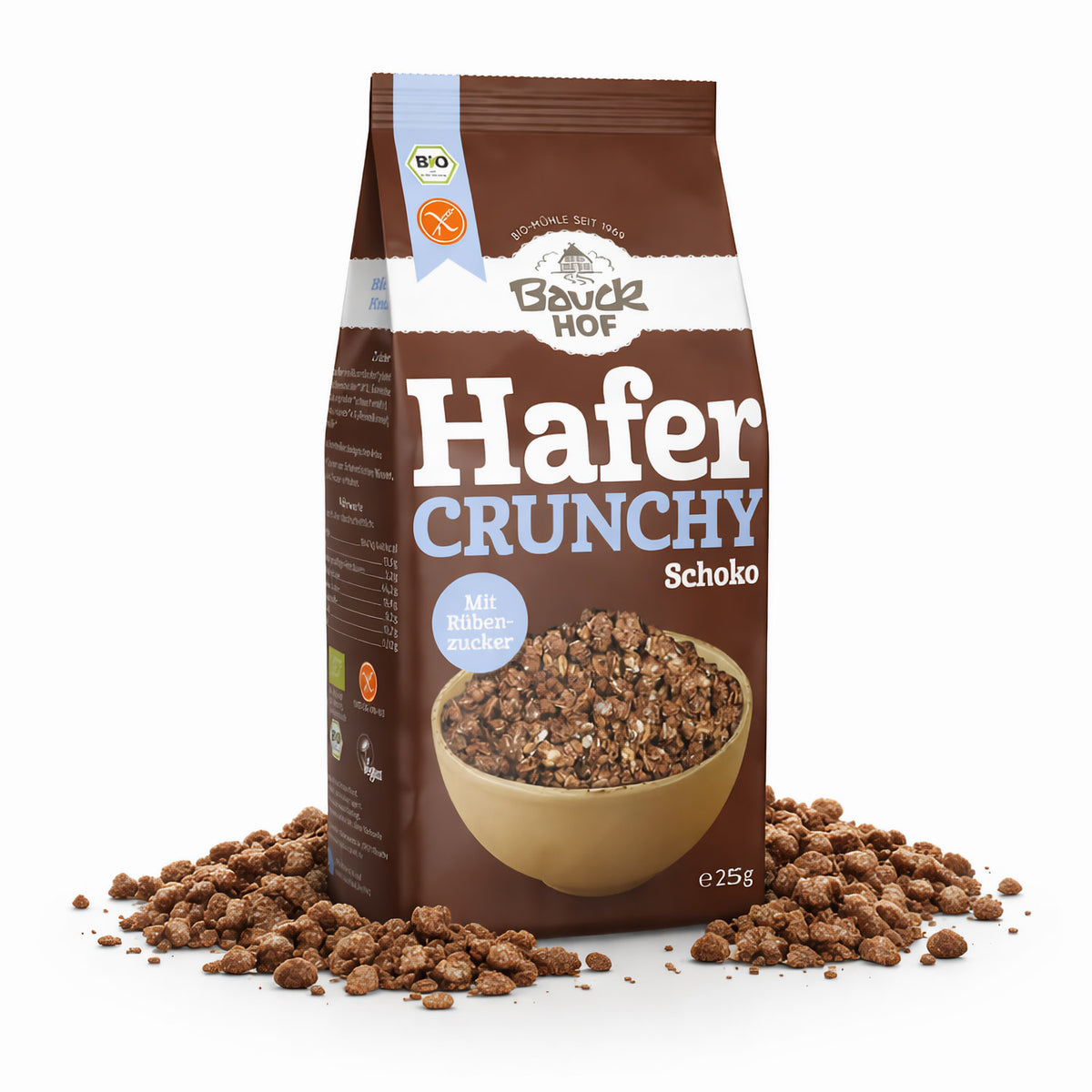 Packung Bauckhof Hafer Crunchy Schoko stehend, umgeben von verstreuten crunchy Schoko-Stückchen auf weißem Hintergrund.