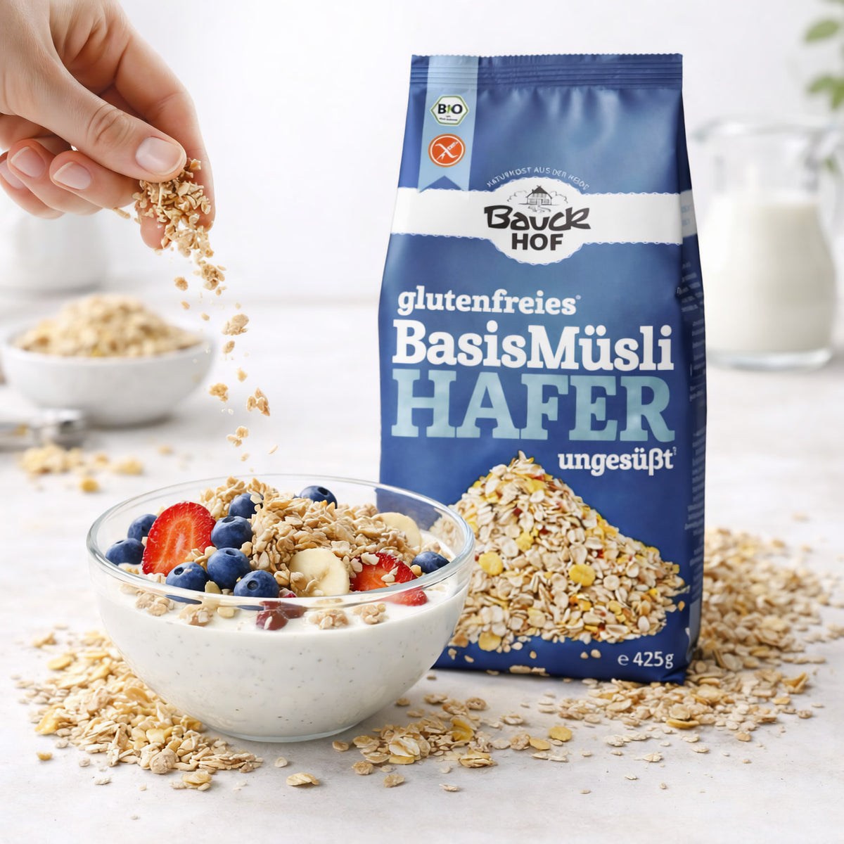 Schale mit Joghurt, frischen Beeren und Bauckhof Hafermüsli Basis glutenfrei, daneben die Produktpackung.