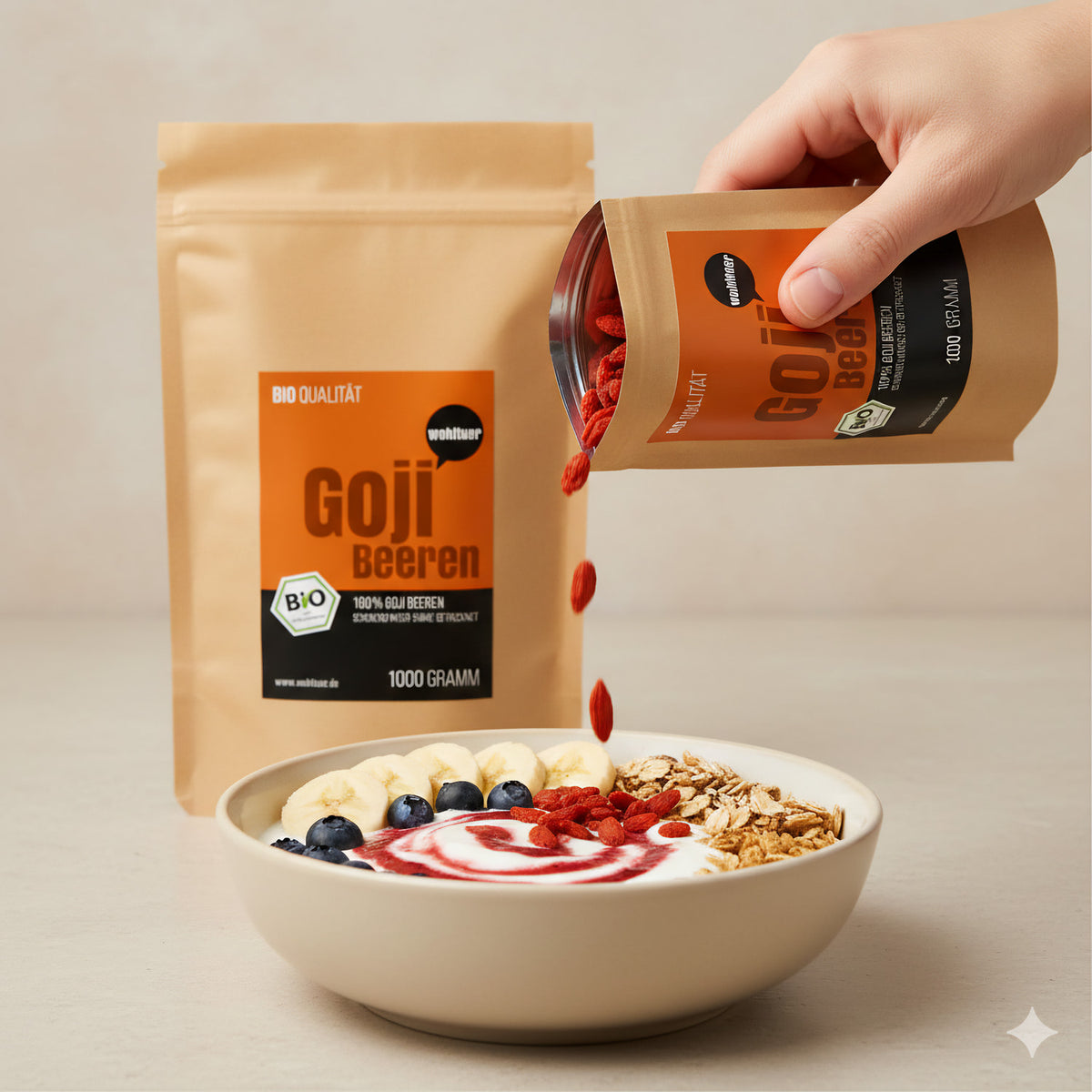 Hand schüttet getrocknete gojibeeren aus wohltuer Beutel in eine Frühstücksschale mit müsli, banane und blaubeeren, im Hintergrund ein weiterer Beutel.