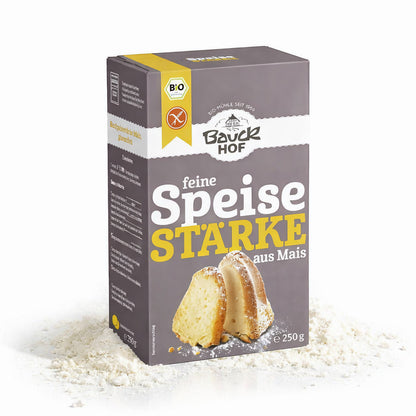 Packung Bauckhof feine Speisestärke aus Mais 250g stehend auf verstreuter Maisstärke, Vorderseite mit Produktabbildung sichtbar