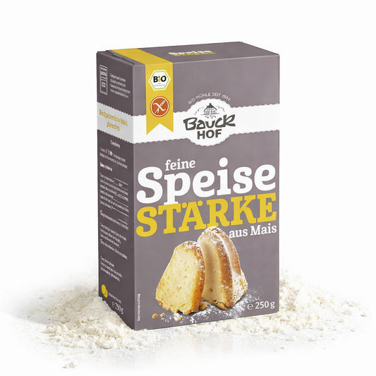 Packung Bauckhof feine Speisestärke aus Mais 250g stehend auf verstreuter Maisstärke, Vorderseite mit Produktabbildung sichtbar