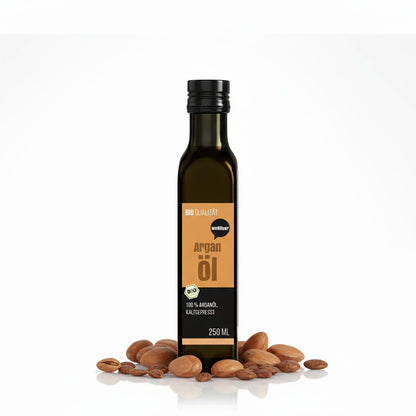 Eine 250ml Flasche wohltuer Arganöl nativ gepresst steht aufrecht, umgeben von ganzen und geöffneten Argan-Nüssen auf weißem Hintergrund.