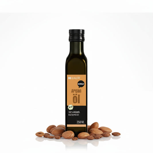 Eine 250ml Flasche wohltuer Arganöl nativ gepresst steht aufrecht, umgeben von ganzen und geöffneten Argan-Nüssen auf weißem Hintergrund.