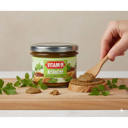 VITAM-R Kräuter Brotaufstrich auf Holzbrett, eine Hand streicht den veganen Aufstrich auf Brot, daneben frische Kräuter.