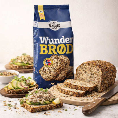 Bauckhof Wunderbrot Backmischung 600g mit angeschnittenem Brotlaib und mehreren belegten Brotscheiben auf Holzbrett.