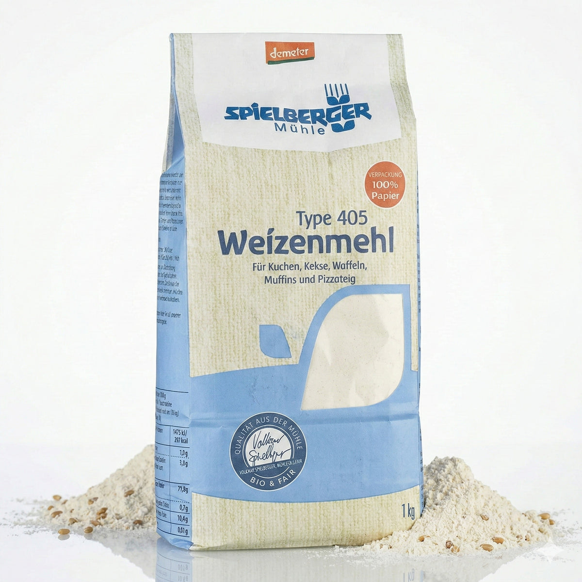 Vorderansicht einer 1000g spielberger Weizenmehl-Tüte, daneben kleine Häufchen Mehl mit sichtbaren Getreidekörnern auf weißem Untergrund.