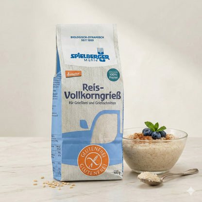 spielberger Reis-Vollkorngrieß neben einer Schale Grießbrei mit Heidelbeeren und Minze, Löffel mit Reis auf hellem Untergrund.