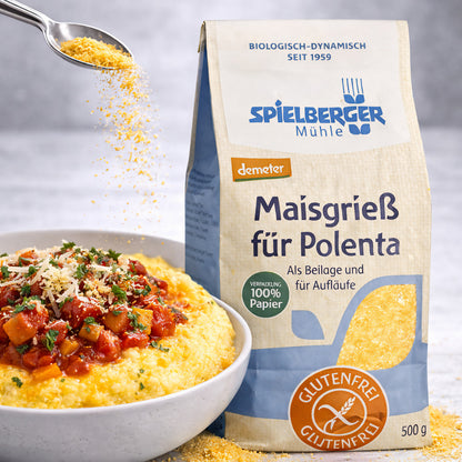 Packung spielberger Polenta Maisgrieß glutenfrei demeter 500g neben einer Schüssel Polenta mit Tomatensoße, darüber wird Maisgrieß gestreut.
