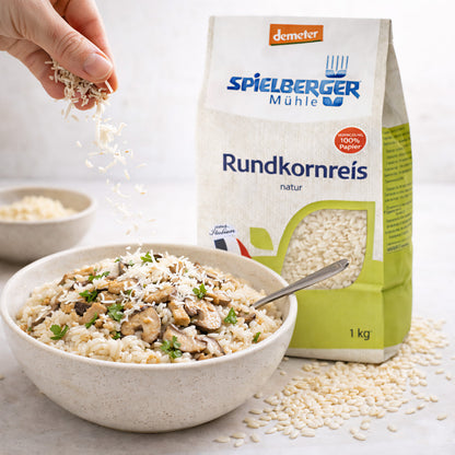 runde Schale mit gekochtem rundkornreis und Pilzen, daneben spielberger rundkornreis 1000g Packung, Hand streut reis darüber