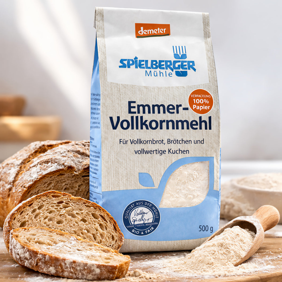 spielberger Emmervollkornmehl 500g vor geschnittenem Vollkornbrot, daneben ein Holzlöffel mit Mehl, geeignet zum Backen.