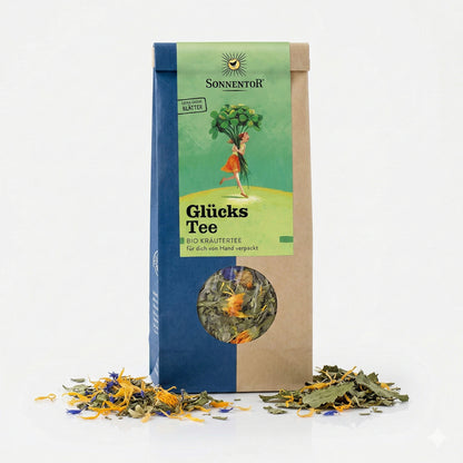 Packung Sonnentor Glücks Kräutertee lose mit Sichtfenster, daneben lose Kräuter auf weißem Untergrund.