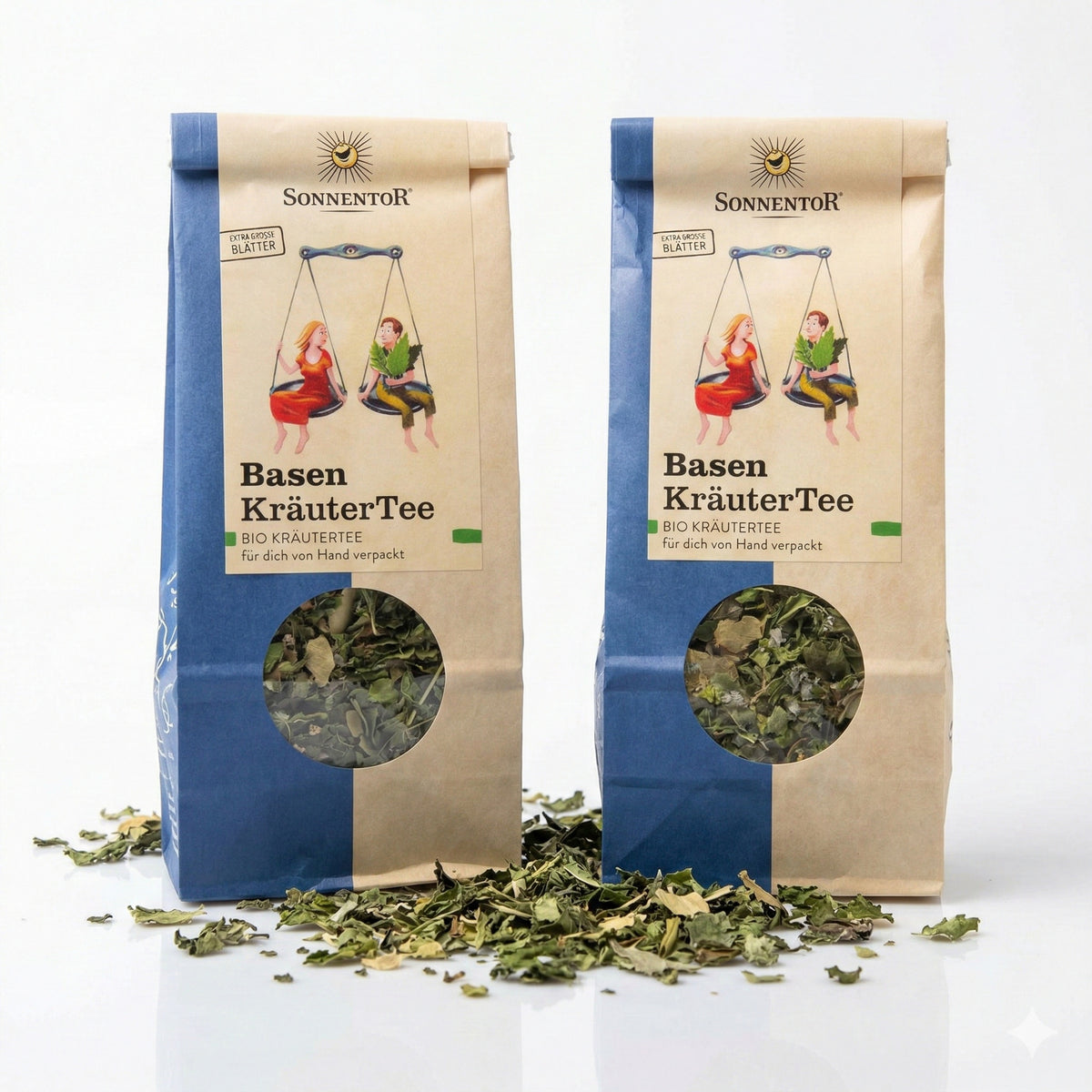 Zwei Packungen Sonnentor Basen Kräutertee lose 2x50g mit Sichtfenster und getrockneten Kräutern auf weißem Untergrund, Produkt und lose Kräuter sichtbar.