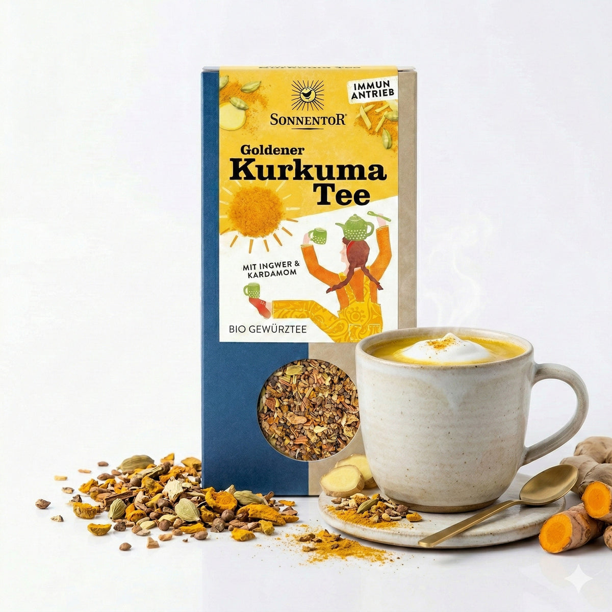 Sonnentor Goldener Kurkuma Tee lose 120g neben einer Tasse Kurkuma-Tee mit Milchschaum, Gewürzen und Teelöffel.