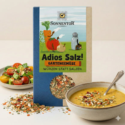 Sonnentor Adios Salz! Gartengemüse 3x60g vor einem Teller Tomatensalat und einer Schüssel Suppe, beide mit der Gewürzmischung bestreut.