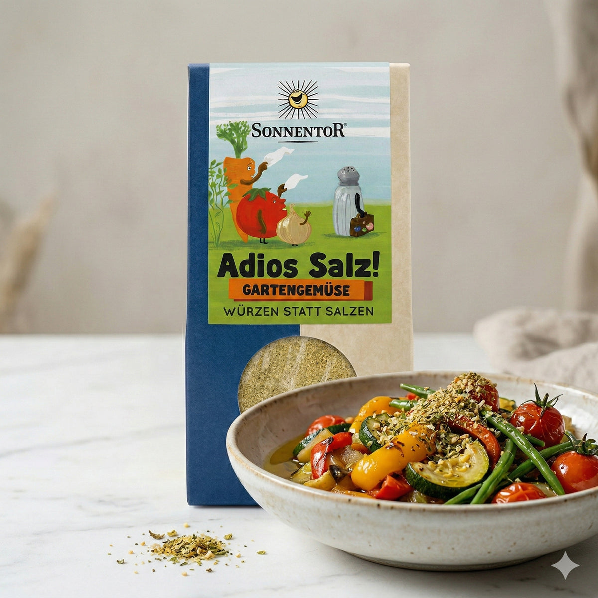 Sonnentor Adios Salz Gartengemüse neben einer Schale mit buntem Gemüsegericht, bestreut mit Gewürzen.