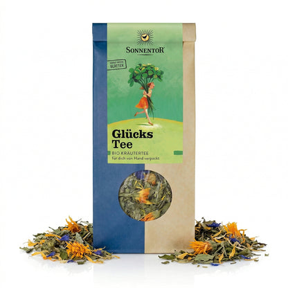 Packung Sonnentor Glückstee lose 2x50g mit Sichtfenster, umgeben von getrockneten Kräutern und Blüten auf weißem Hintergrund.