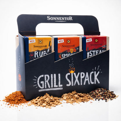 Sonnentor Grill Sixpack Gewürzset in schwarzer Verpackung mit sichtbaren Kräuter-Mischungen und Gewürzhäufchen davor.