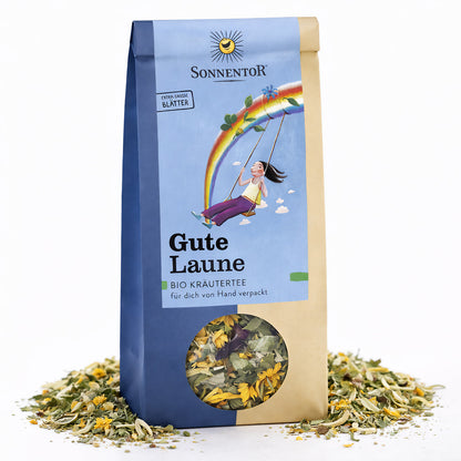 Sonnentor Gute Laune Kräutertee lose in 50g-Packung, stehend auf weißem Hintergrund, mit Sichtfenster und verstreuten Kräutern um die Verpackung.