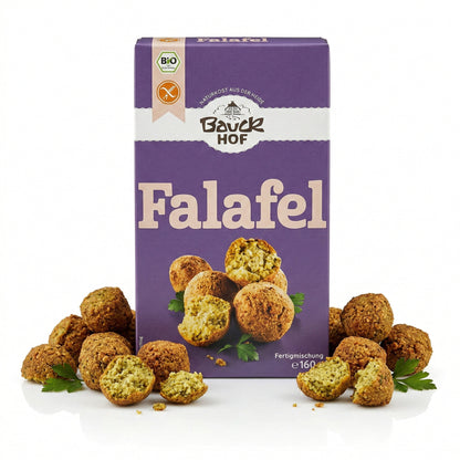 Packung Bauckhof Falafel Mischung glutenfrei, umgeben von angerichteten Falafel-Bällchen und Petersilie auf weißem Hintergrund.