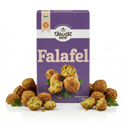 Packung Bauckhof Falafel Mischung glutenfrei, umgeben von angerichteten Falafel-Bällchen und Petersilie auf weißem Hintergrund.