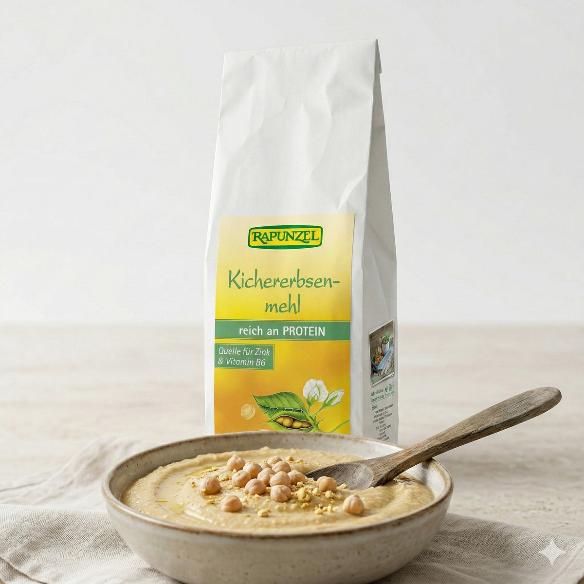 Geröstetes Bio Kichererbsenmehl von Rapunzel in 500g-Packung, für gesunde Kochrezepte, zeigt die Verpackung und Mehl im Behälter.